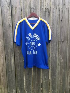 This shirt is simple yet looks awesome and is perfect for anyone that loves vintage sports clothing. It is in good condition with some snagging and some print chipping on the back, but has no rips, holes, stains or smells. Measurements: Pit to pit: 22 1/2 inches Collar to bottom front: 22 1/4 inches Collar to bottom back: 26 inches Size on tag: XL Blue Throwback Sports T-shirt, Throwback Blue Sports T-shirt, Blue Throwback T-shirt For Sports Season, Blue Throwback T-shirt For Sports, Retro Sports Top With Team Logo, Vintage Tops With Team Name For Sports Season, 90s Blue T-shirt For College, 90s Style Blue T-shirt For College, Retro Blue Sports T-shirt