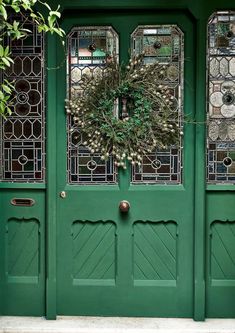 a green front door with a wreath on the top and two glass windows above it