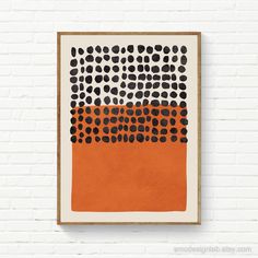 an orange and black painting hanging on a brick wall