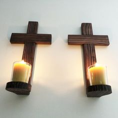 two candles are lit on the cross wall sconces, one is yellow and the other is brown