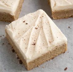 four pieces of cake sitting on top of a piece of parchment paper with white frosting