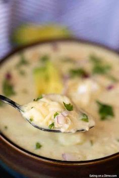 a spoon full of soup with broccoli and cheese on it, in a bowl