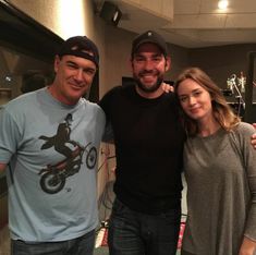 three people standing next to each other in front of a recording equipment room with microphones