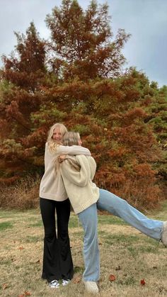 two people standing in the grass with their arms around each other