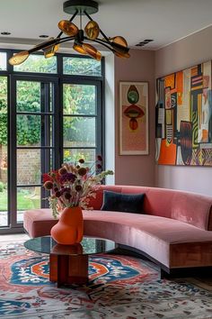 a living room with pink couches and art on the wall behind it's glass table