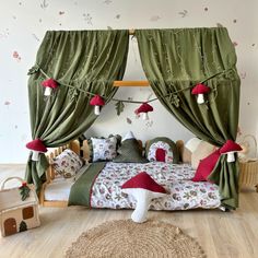 a bed with green curtains and red pillows on it in a room that has wooden floors