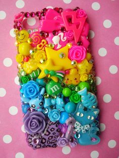 a cell phone case with many different colors and designs on the front, sitting on a polka dot surface