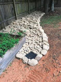 a garden bed made out of rocks in the middle of a fenced backyard area