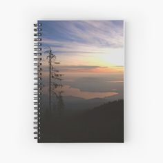 the sun is setting in the mountains with clouds and trees on it spiral bound notebook