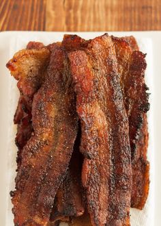 bacon strips on a white plate sitting on a wooden table