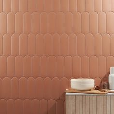 a bathroom with pink tiles on the wall and a white bowl in front of it