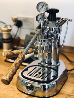 an espresso machine sitting on top of a wooden table next to a clock