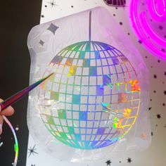 a person is holding a pair of scissors to cut out a disco ball ornament