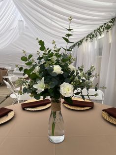 a vase filled with flowers sitting on top of a table next to place mats and place settings