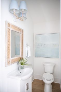 a bathroom with a sink, toilet and painting on the wall in it's corner