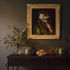 a painting hangs on the wall above a table with fruit and flowers in front of it