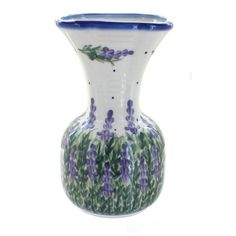 a blue and white vase with purple flowers on it's rim, against a white background