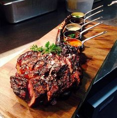 a steak on a cutting board with sauces and garnishes next to it