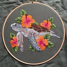 a close up of a embroidery on a piece of cloth with flowers and a turtle