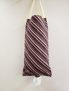 a striped bag hanging from a hook on a white wall with a string attached to it