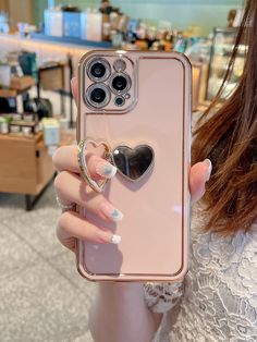 a woman holding up her phone case with a heart on the front and fingernails attached to it