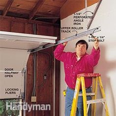 a man standing on a stepladder in front of a garage door holding onto the ceiling