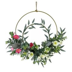 a wreath with flowers and greenery hanging from a metal ring on a white background