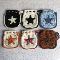 four crocheted purses are lined up on a table top, each with different designs and colors