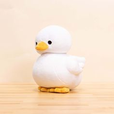 a white stuffed duck sitting on top of a wooden table