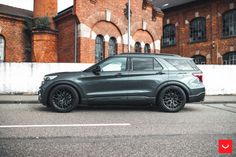 a grey ford explorer parked in front of a brick building with black rims on it