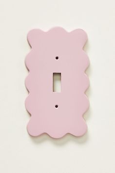 a pink scallop shaped light switch plate on a white wall with a black hole in the middle