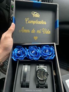 a person holding up a watch in a box with blue roses on the inside of it