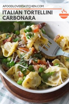 a bowl filled with tortelli and vegetables on top of a wooden cutting board