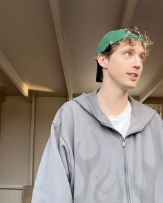 a young man wearing a green hat and grey jacket