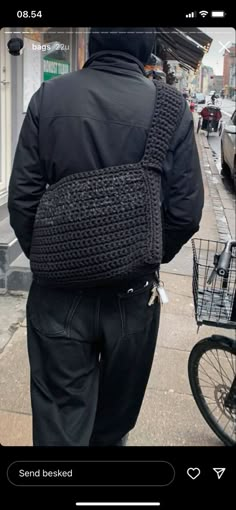 a man walking down the street with a crocheted back pack