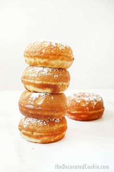 three donuts stacked on top of each other in front of a white background with powdered sugar