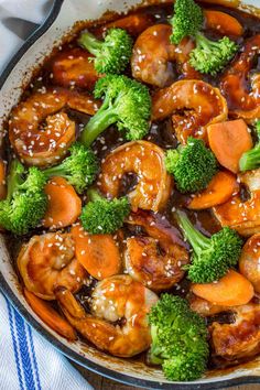 the dish has broccoli, carrots and shrimp in it with sauce on top