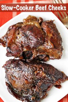 two pieces of barbecue ribs on a white plate with fork and red checkered table cloth