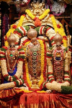 an elaborately decorated statue in the center of a room filled with flowers and garlands