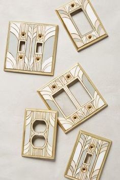 four decorative switchplates and one outlet cover in gold with art deco designs on them