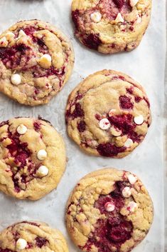 cookies with white chocolate chips and cranberry fillings on a sheet of wax paper