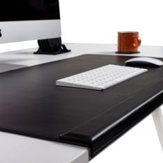 a computer desk with a keyboard, mouse and cup on it's side table