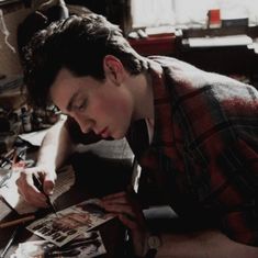 a young man sitting at a desk writing on paper