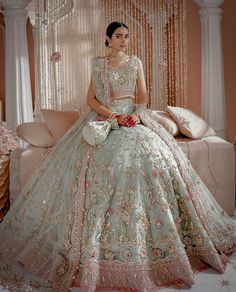 a woman sitting on top of a couch wearing a dress and holding a bouquet in her hand