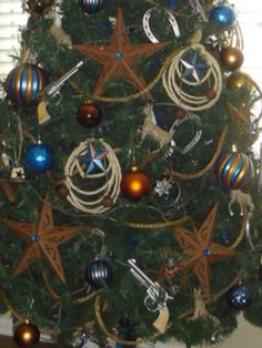 a christmas tree decorated with ornaments and star decorations in blue, gold and silver colors