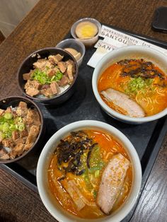 three bowls of food on a tray with chopsticks