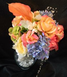 a vase filled with lots of colorful flowers on top of a black cloth covered table