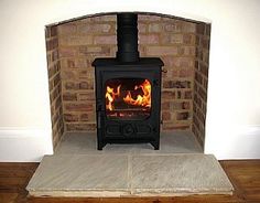 a wood burning stove sitting inside of a brick fireplace