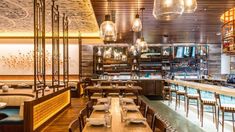 an empty restaurant with wooden tables and chairs, hanging lights above the dining room table