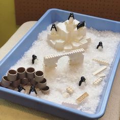 a blue tray filled with lots of fake snow and plastic toys on top of it